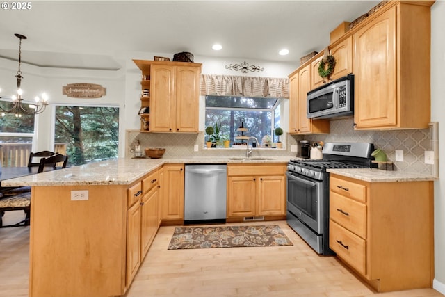 kitchen with sink, appliances with stainless steel finishes, hanging light fixtures, kitchen peninsula, and light brown cabinets