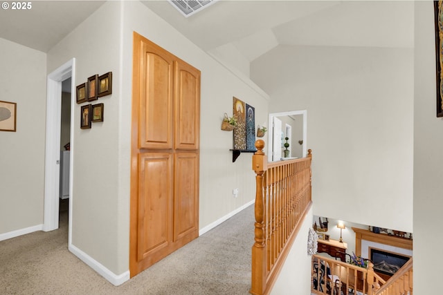 hall with lofted ceiling and light carpet