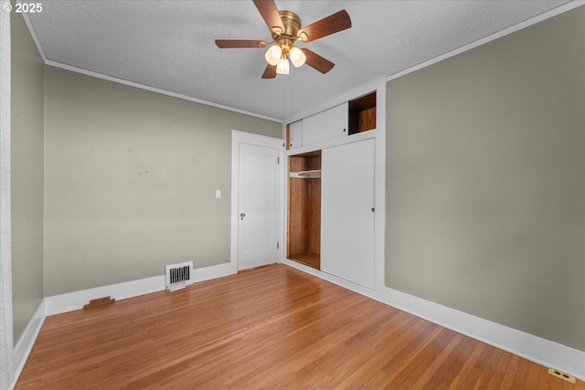 7406 N Fiske Ave, Portland, OR 97203 - unfurnished bedroom with light wood-type flooring, a closet, crown molding, a textured ceiling, and a ceiling fan