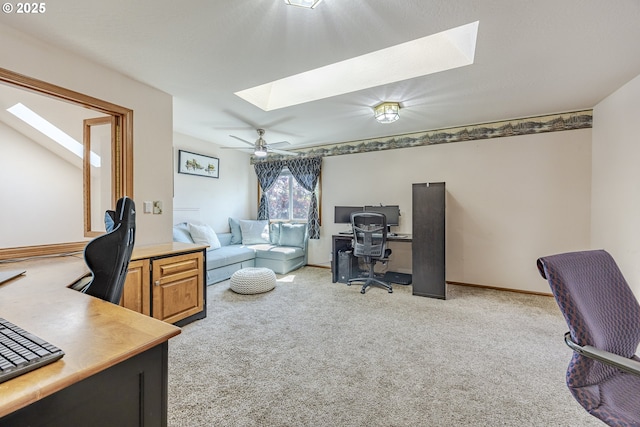 office space featuring a skylight, light colored carpet, and baseboards