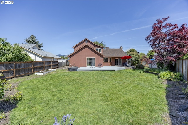 rear view of house with a lawn, a wooden deck, a fenced backyard, and a chimney