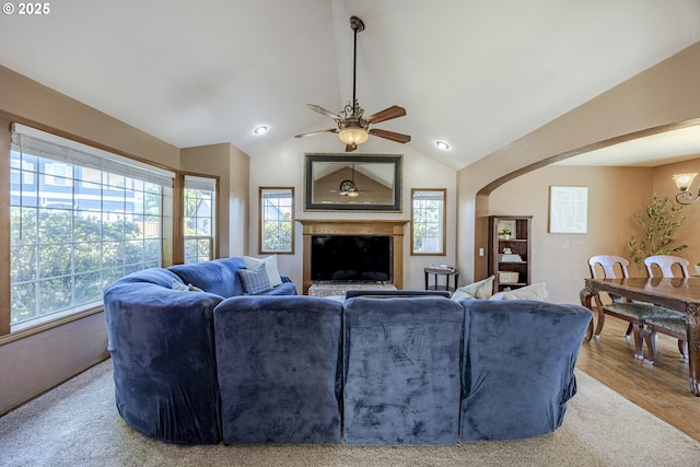 living area with a ceiling fan, arched walkways, a healthy amount of sunlight, and lofted ceiling