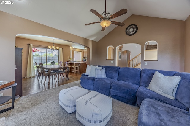 living area with carpet floors, arched walkways, ceiling fan with notable chandelier, and high vaulted ceiling