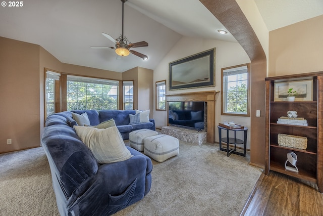 living area with vaulted ceiling, baseboards, a ceiling fan, and a glass covered fireplace