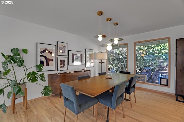 dining space featuring light wood finished floors and baseboards