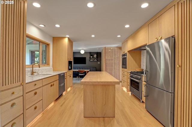 kitchen with recessed lighting, appliances with stainless steel finishes, a sink, and light brown cabinetry