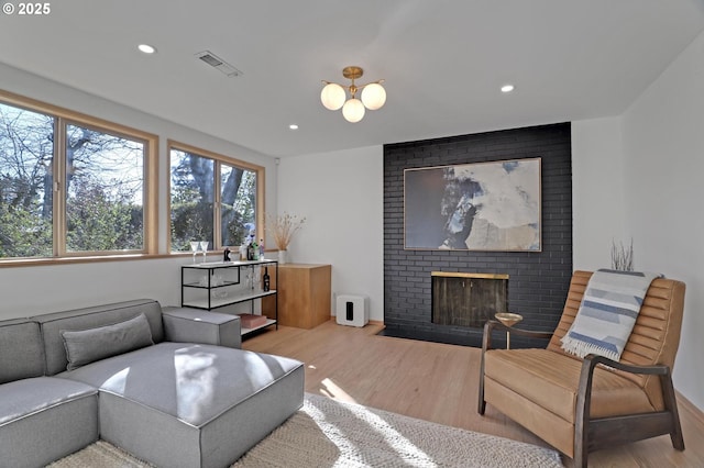 living room featuring recessed lighting, a brick fireplace, visible vents, and wood finished floors