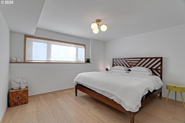 bedroom featuring an inviting chandelier, wood finished floors, and baseboards