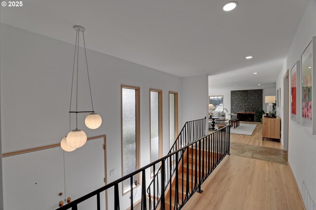 hall with recessed lighting, visible vents, wood finished floors, and an upstairs landing