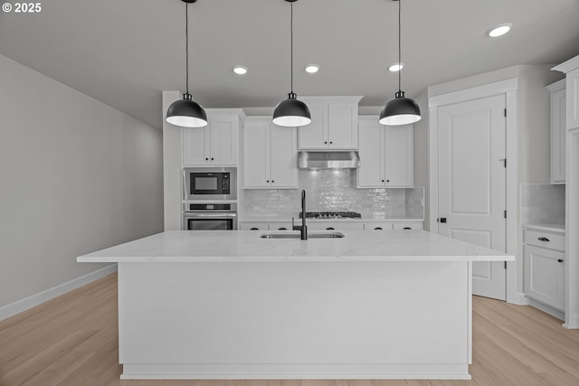 kitchen with extractor fan, white cabinetry, decorative light fixtures, a center island with sink, and stainless steel appliances