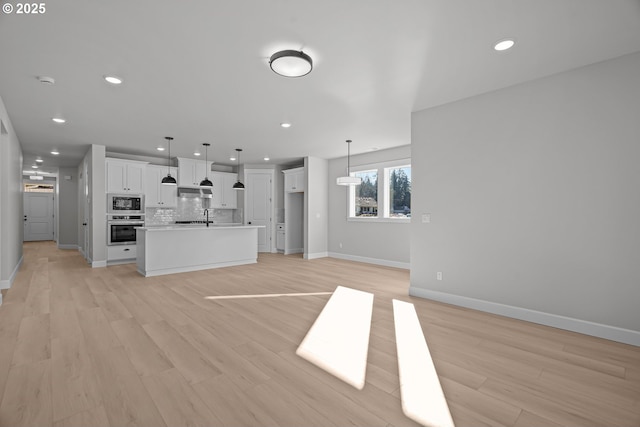 unfurnished living room with sink and light hardwood / wood-style floors