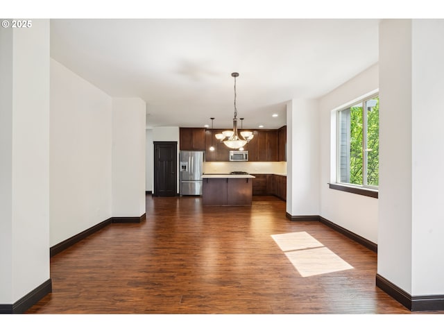 kitchen featuring a center island, light countertops, an inviting chandelier, stainless steel appliances, and dark wood-type flooring