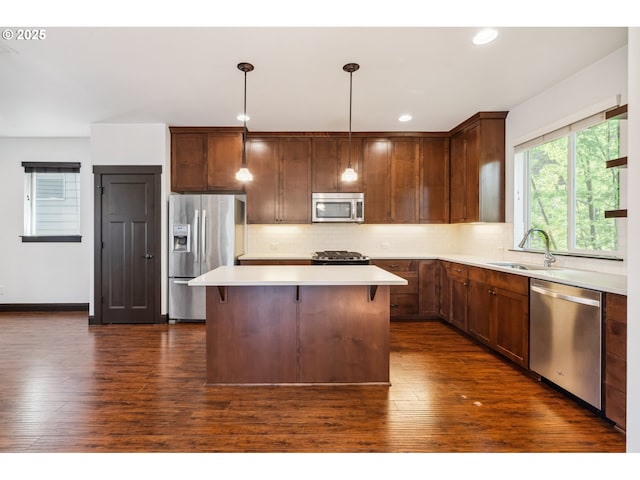 kitchen featuring appliances with stainless steel finishes, tasteful backsplash, dark wood finished floors, a sink, and light countertops
