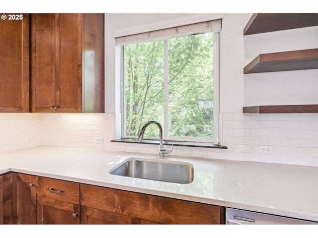 kitchen with open shelves, light stone counters, a sink, brown cabinetry, and decorative backsplash