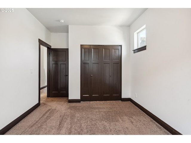 unfurnished bedroom with carpet flooring, baseboards, and a closet
