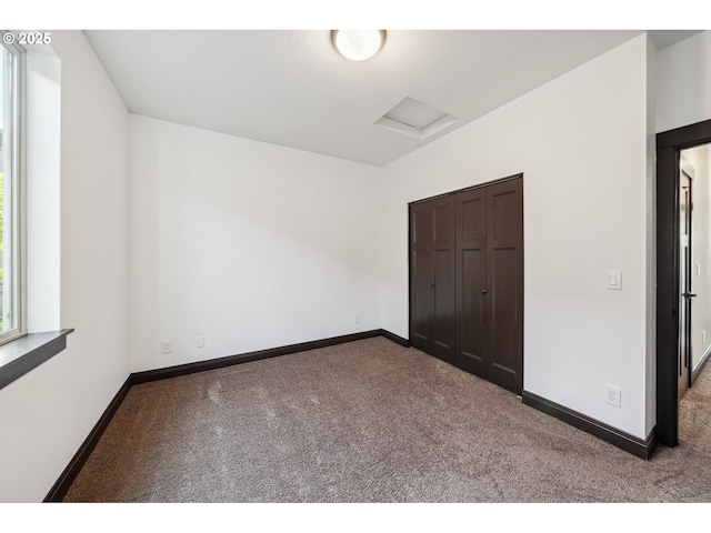 unfurnished bedroom featuring carpet floors, baseboards, and attic access