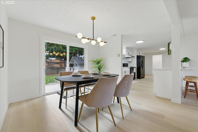 dining space featuring an inviting chandelier, light hardwood / wood-style floors, and a textured ceiling