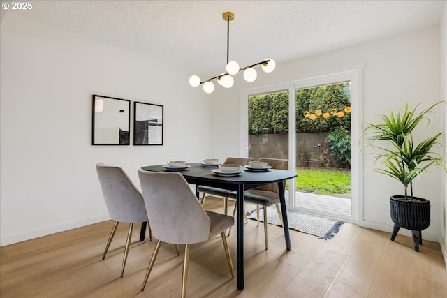 dining space featuring light hardwood / wood-style flooring, a chandelier, and a textured ceiling