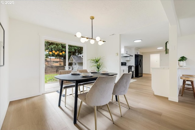 dining room with an inviting chandelier, a textured ceiling, and light hardwood / wood-style floors