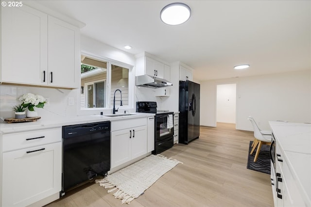 kitchen with white cabinetry, sink, black appliances, and light stone countertops