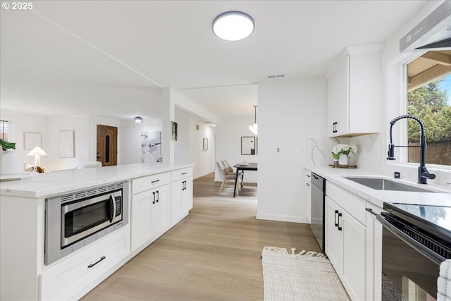 kitchen with stainless steel appliances, kitchen peninsula, sink, and white cabinets