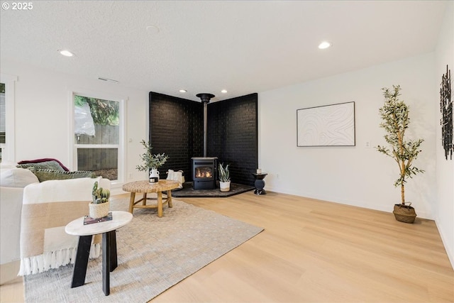 living room featuring hardwood / wood-style flooring, a textured ceiling, and a wood stove