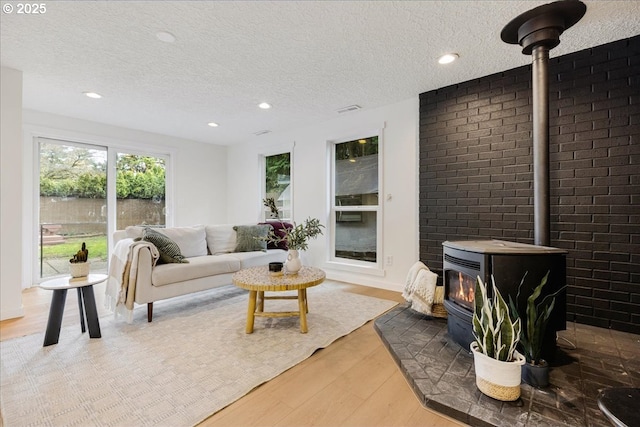 living room featuring hardwood / wood-style flooring, a wood stove, and a textured ceiling