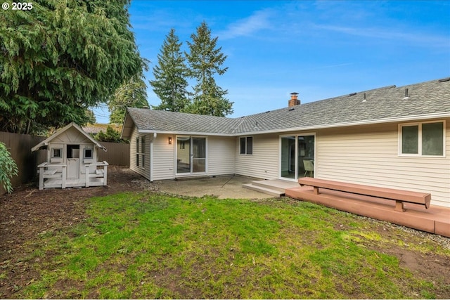 rear view of property featuring a patio, a wooden deck, a lawn, and a storage shed