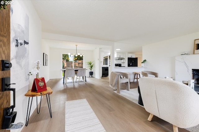 dining space featuring a fireplace, a chandelier, light hardwood / wood-style flooring, and a textured ceiling