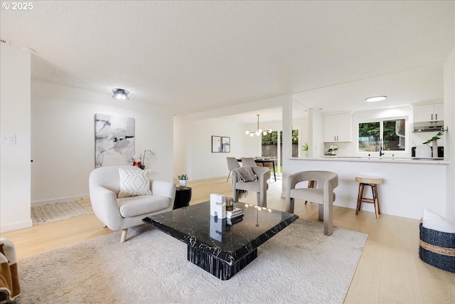 living room featuring an inviting chandelier, a textured ceiling, and light wood-type flooring