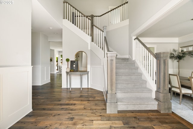 1314 NW Abernethy Rd, Portland, OR 97229 - stairway with wood finished floors, wainscoting, a towering ceiling, crown molding, and a decorative wall