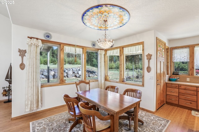 52135 E Terra Fern Dr, Sandy, OR 97055 - dining room featuring healthy amount of natural light, light wood-type flooring, a chandelier, and a textured ceiling