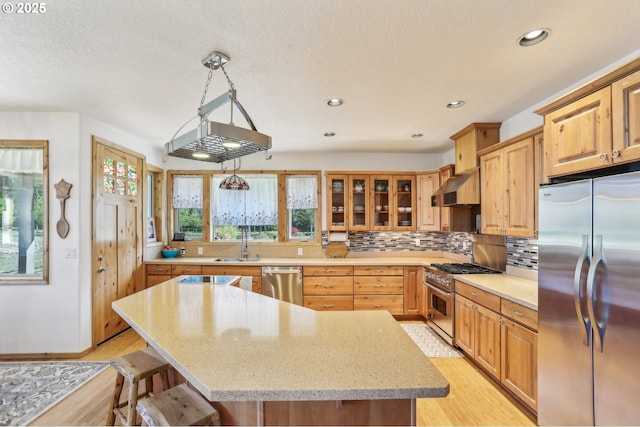 52135 E Terra Fern Dr, Sandy, OR 97055 - kitchen featuring appliances with stainless steel finishes, light wood-style floors, decorative backsplash, light stone counters, and recessed lighting