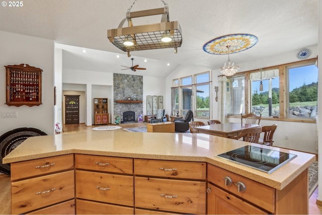52135 E Terra Fern Dr, Sandy, OR 97055 - kitchen featuring a fireplace, black electric stovetop, ceiling fan, lofted ceiling, and light stone counters