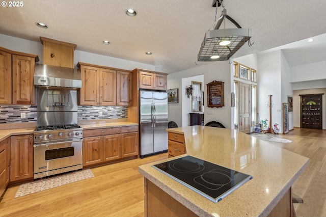 52135 E Terra Fern Dr, Sandy, OR 97055 - kitchen featuring appliances with stainless steel finishes, wall chimney exhaust hood, a center island, light wood-type flooring, and backsplash