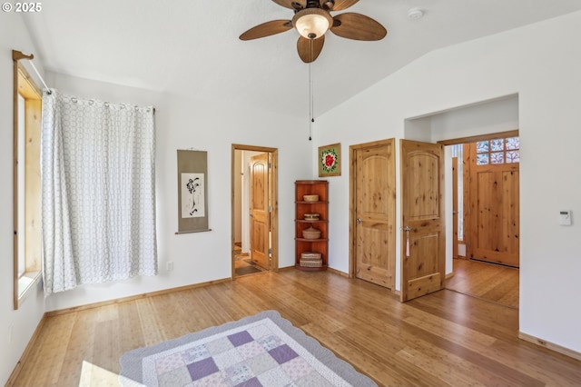 unfurnished bedroom with wood finished floors, lofted ceiling, baseboards, and a ceiling fan