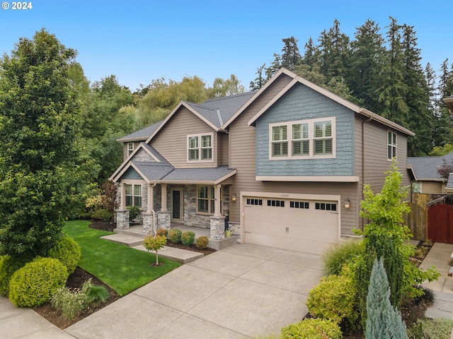 craftsman house featuring a porch, a garage, and a front lawn