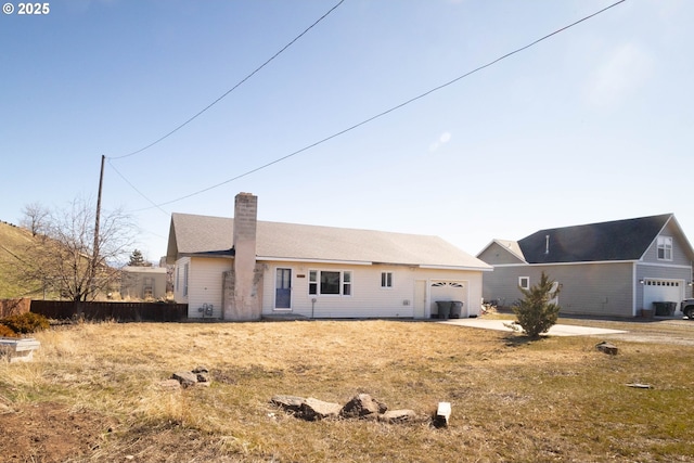 view of front of home with a garage, cooling unit, and a chimney