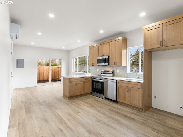 kitchen with an AC wall unit, a sink, electric panel, stainless steel appliances, and a peninsula