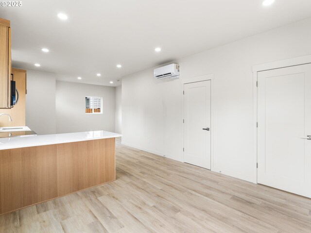 kitchen featuring light countertops, a wall unit AC, recessed lighting, a peninsula, and light wood-style floors