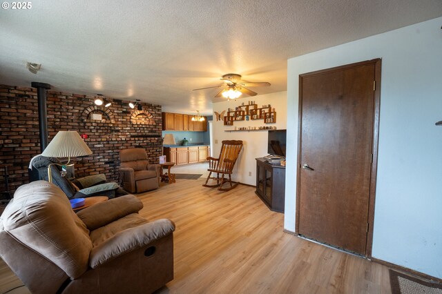 1630 SW Riverhill Dr, Hermiston, OR 97838 - living room with a wood stove, light wood-style flooring, ceiling fan, a textured ceiling, and brick wall