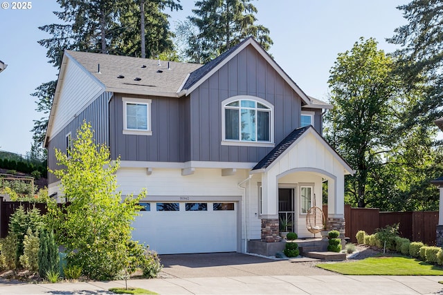 view of front of house with board and batten siding, fence, driveway, stone siding, and an attached garage