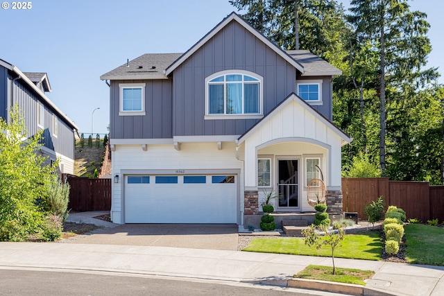 view of front of property with fence, driveway, an attached garage, stone siding, and board and batten siding