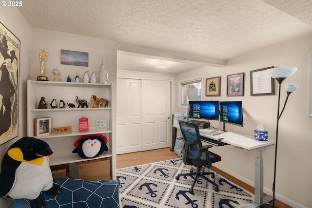 office space featuring a textured ceiling, baseboards, and wood finished floors