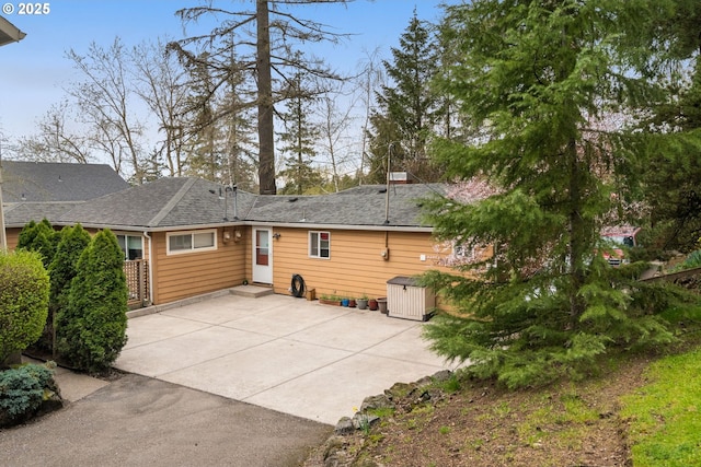back of house featuring a shingled roof and a patio area