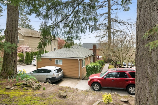 view of side of home featuring a chimney and roof with shingles