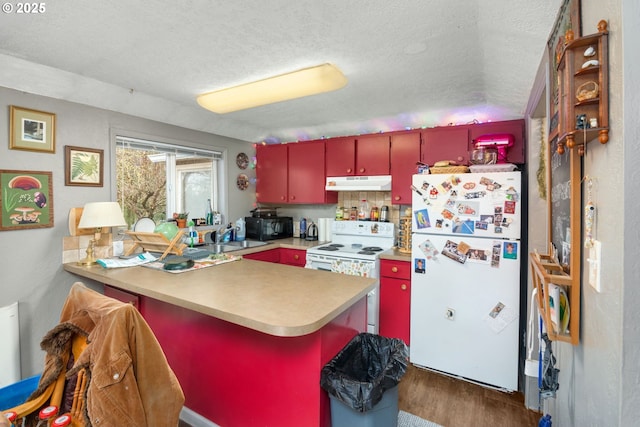 kitchen with wood finished floors, a peninsula, red cabinetry, under cabinet range hood, and white appliances