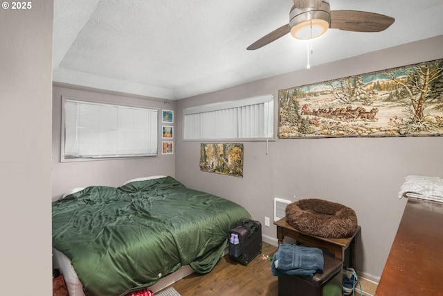 bedroom featuring baseboards, wood finished floors, ceiling fan, and a textured ceiling