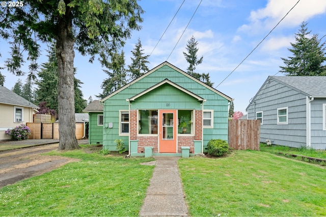 bungalow-style house with brick siding, fence, and a front yard