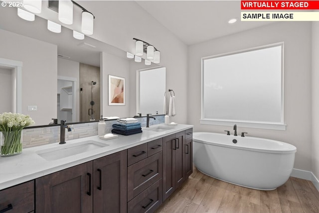 bathroom featuring vanity, hardwood / wood-style floors, backsplash, and separate shower and tub